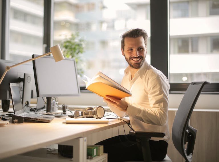 Person at a desk holding a journal